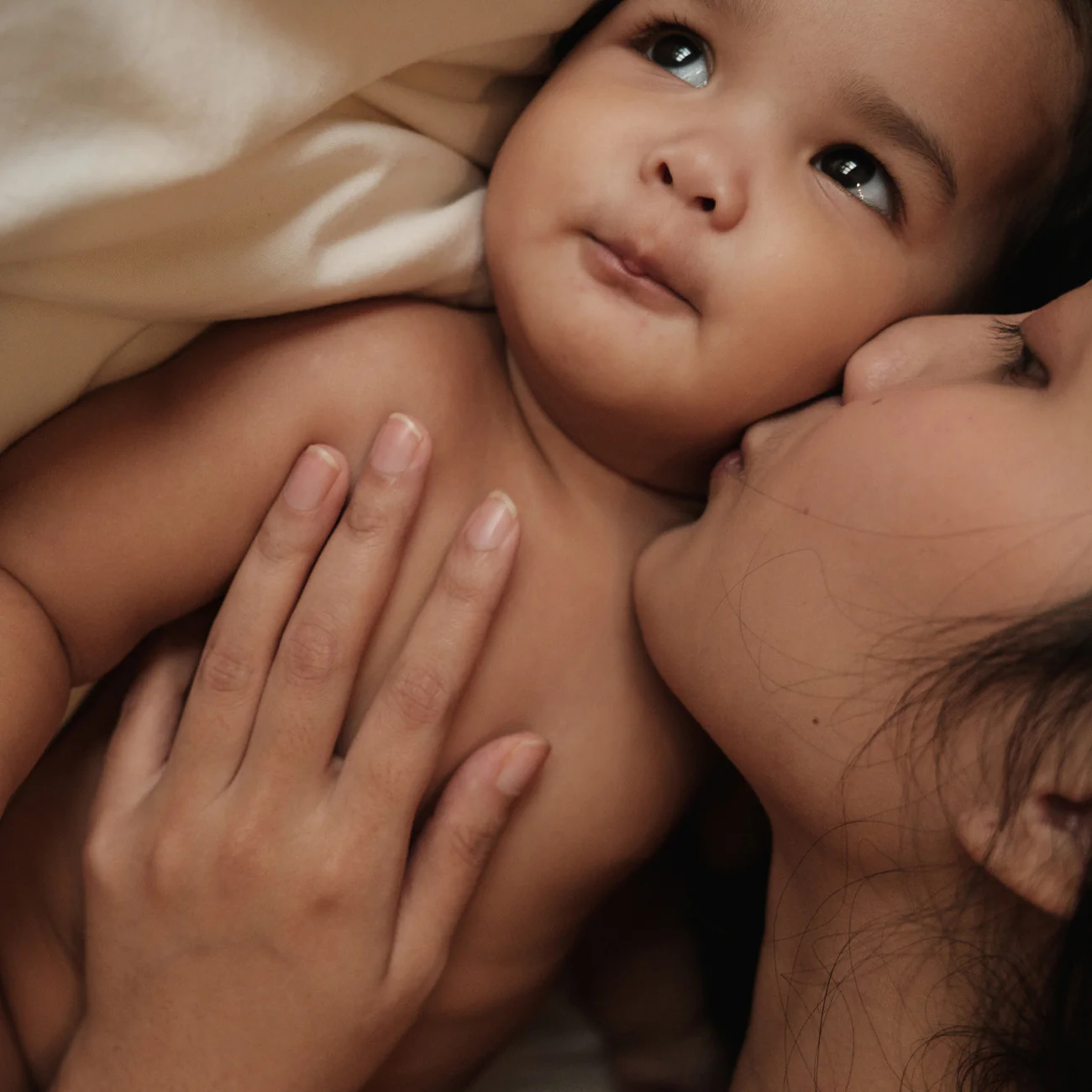 Maman câlinant tendrement son bébé, symbolisant l'amour et le lien renforcé dans la période post-partum.